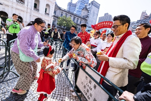 圖為巡游隊伍沿途給游客送出祝福吉祥的金元寶。澳門特區(qū)政府新聞局供圖