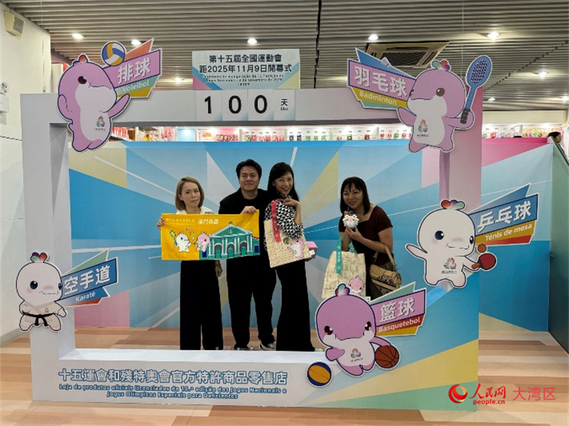 圖為特許商品零售店顧客與十五運會開幕倒計時牌合影。人民網(wǎng)記者 富子梅攝