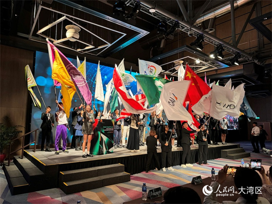 圖為與會青年代表在開幕式上揮舞各自學(xué)校的旗幟。人民網(wǎng)記者 富子梅攝