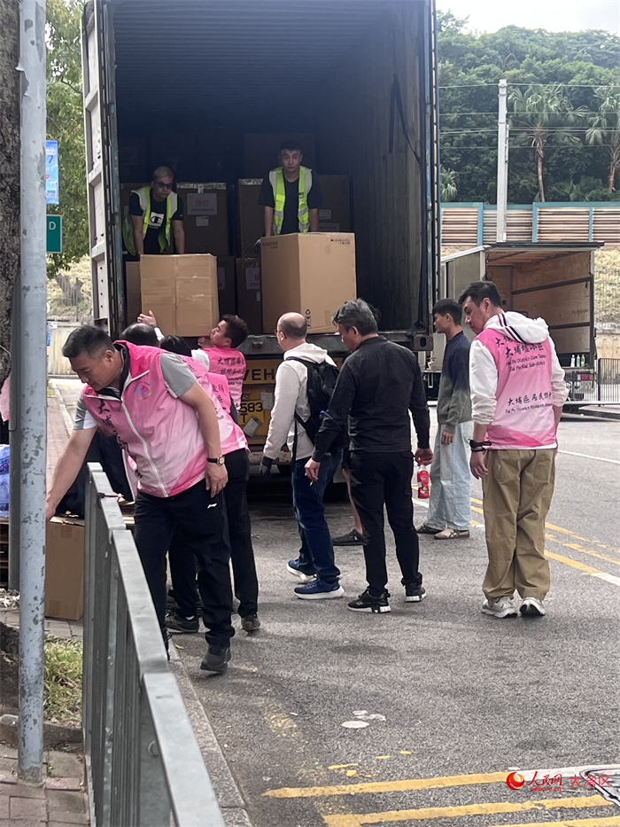 庇護中心外，關愛隊和義工正在搬運物資。人民網記者 王堯攝