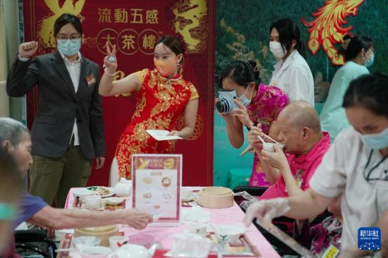 5月24日，在香港松悅園耆和護養(yǎng)院，香港樂齡社企“軟餐俠”的職員們扮演成“茶樓”經(jīng)理、廚師和接待員，為老人家提供沉浸式茶樓就餐體驗。新華社發(fā)（王申 攝）
