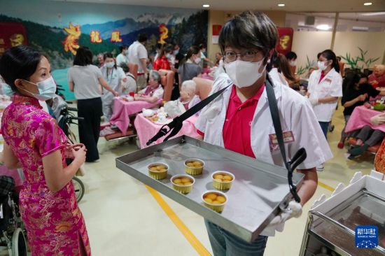 5月24日，在香港松悅園耆和護養(yǎng)院，身穿白衫的伙計在“茶樓”售賣茶點，端茶倒水。新華社發(fā)（王申 攝）