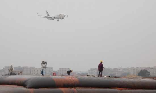 　　2025年1月23日，一架準(zhǔn)備降落的飛機(jī)經(jīng)過(guò)白云機(jī)場(chǎng)擴(kuò)建工程施工現(xiàn)場(chǎng)。新華社記者 田建川 攝