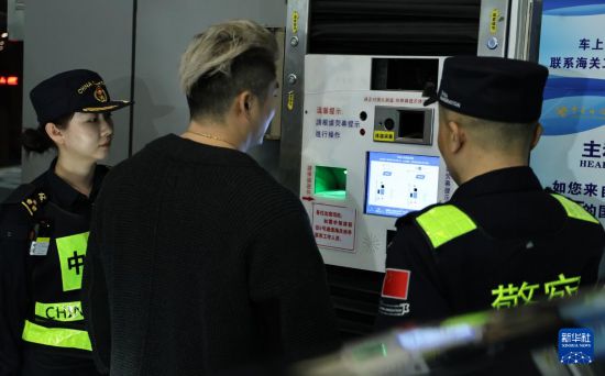 12月23日，“粵車南下”入境香港市區(qū)的首位通關(guān)車主彭先生（中）在“一站式”通道辦理通關(guān)手續(xù)。新華社記者 黃國保 攝