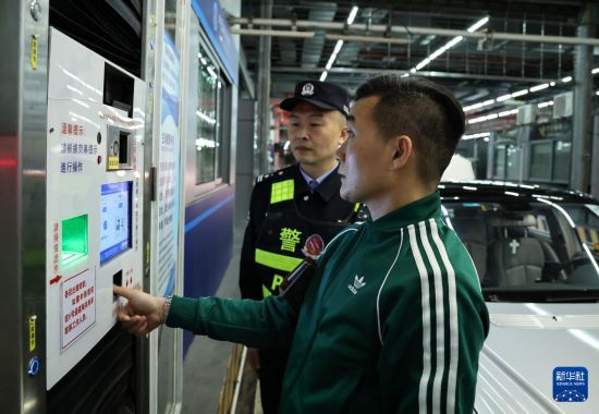 12月23日零時(shí)，“粵車南下”入境香港市區(qū)的通關(guān)車主曹先生（前）在“一站式”通道辦理通關(guān)手續(xù)。新華社記者 黃國保 攝