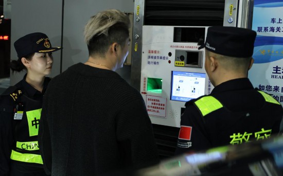 12月23日，“粵車南下”入境香港市區(qū)的首位通關(guān)車主彭先生（中）在“一站式”通道辦理通關(guān)手續(xù)。新華社記者 黃國保 攝